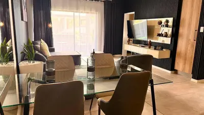 a dining room with a glass table and chairs at Forest Haven in Midrand