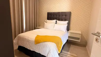 a bedroom with a bed with a yellow and white blanket at Forest Haven in Midrand
