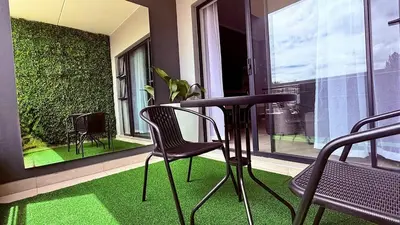 a table and chairs on a balcony with green grass at Forest Haven in Midrand