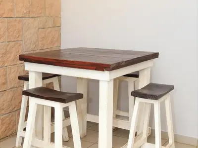 a wooden table with two stools next to it at Phomola Guesthouse in Brits