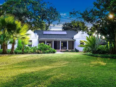 a white house with a lawn in front of it at Phomola Guesthouse in Brits