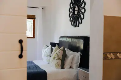 a bedroom with a bed with white sheets and pillows at Ingaadi in Pretoria
