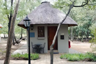 a small hut with a thatched roof and a table at Ingaadi in Pretoria