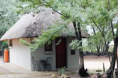a small hut with a thatched roof and a table and chairs at Ingaadi in Pretoria