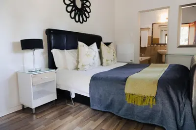 a bedroom with a bed and a night stand with a lamp at Ingaadi in Pretoria