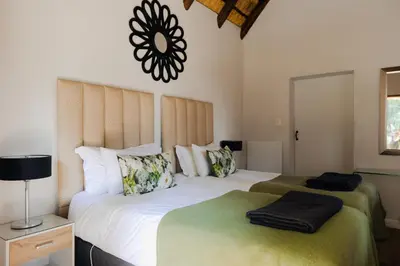 a bedroom with a large bed with white sheets and pillows at Ingaadi in Pretoria