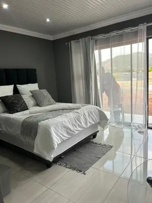 a bedroom with a bed and a person looking out the window at Okuhle guesthouse in Mahlakwena
