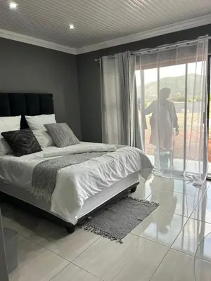 a bedroom with a bed and a person looking out the window at Okuhle guesthouse in Mahlakwena