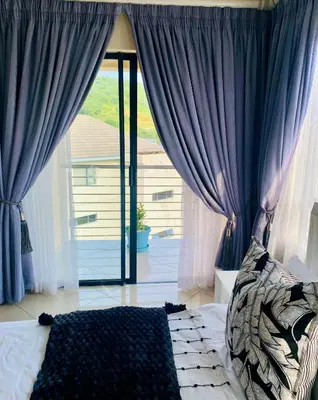 a bedroom with blue curtains and a large window at The Ridge At Mountain View Vacation Home in Boschrand