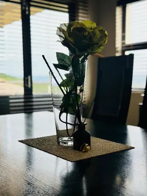 a vase with a yellow rose in it on a table at The Ridge At Mountain View Vacation Home in Boschrand
