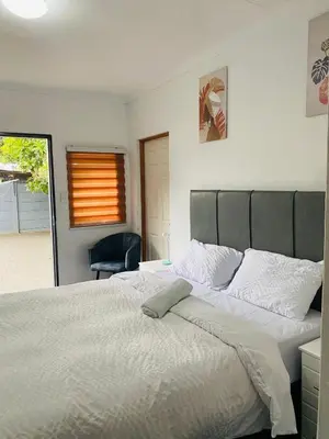 a bedroom with a large white bed and a chair at Linies guest house in Benoni