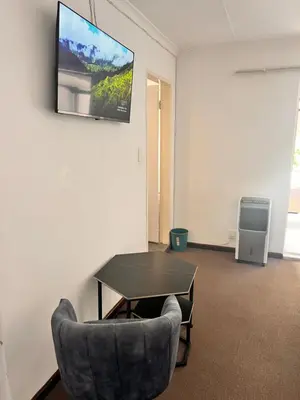 a room with a table and a chair and a tv at Linies guest house in Benoni