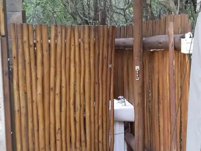 a wooden fence with a toilet in front of it at My Bush Camp in Settlers