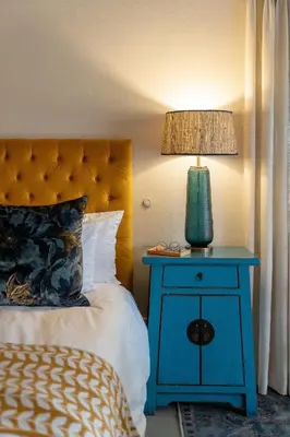 a bed with a blue end table with a lamp on it at Sashwa River of Stars Plant-Based Wellness Safari Lodge in Hoedspruit
