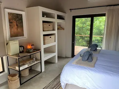 a bedroom with a bed and a large window at Sashwa River of Stars Plant-Based Wellness Safari Lodge in Hoedspruit