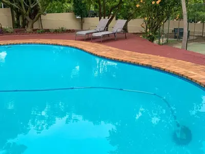 a blue swimming pool with two chairs in a yard at The Pillows Suites Villa in Pretoria