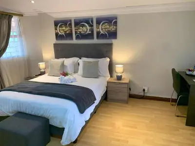 a bedroom with a large white bed with two lamps at The Pillows Suites Villa in Pretoria