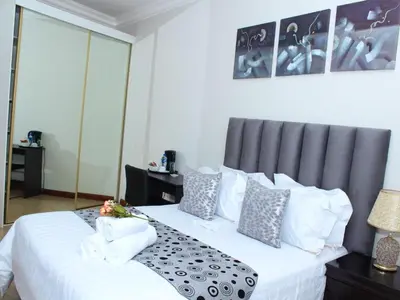a bedroom with a bed with white sheets and pillows at The Pillows Suites Villa in Pretoria