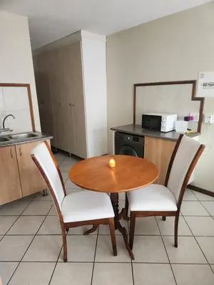 a kitchen with a wooden table and two chairs at Executive Harmonic Studio in Midrand
