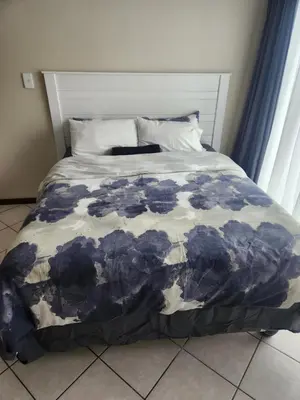 a bed with a blue and white blanket on it at Executive Harmonic Studio in Midrand