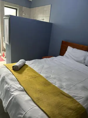 a bed with a yellow blanket on top of it at Sherotha Homestay in Louis Trichardt