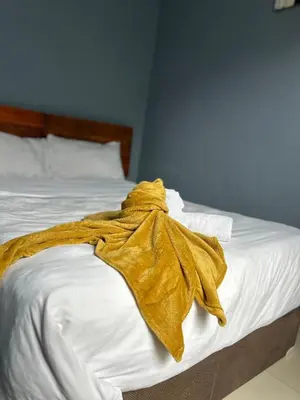 a yellow blanket laying on a white bed at Sherotha Homestay in Louis Trichardt