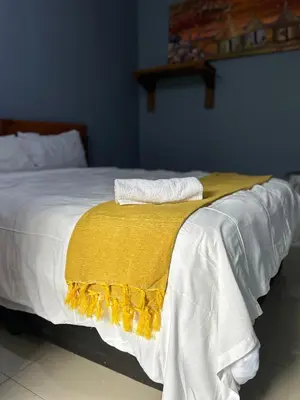 a bed with a yellow blanket on top of it at Sherotha Homestay in Louis Trichardt