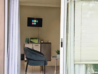 a chair and a desk with a television on a wall at The Barn Haven in Kyalami