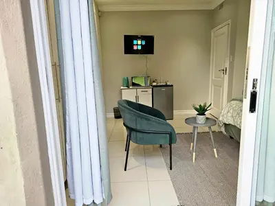 a room with a chair and a table and a television at The Barn Haven in Kyalami