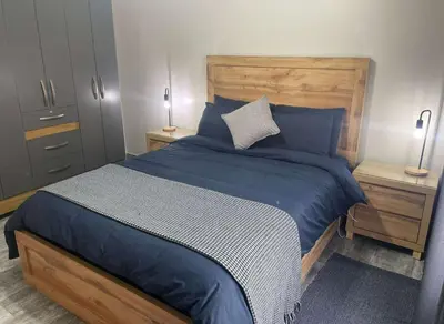 a bedroom with a bed with blue sheets and two lamps at Hantam Suites in Centurion