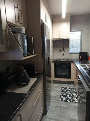 a kitchen with wooden cabinets and a stove top oven at Hantam Suites in Centurion