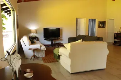a living room with a white couch and a tv at The Goat House Farmstay in Nelspruit