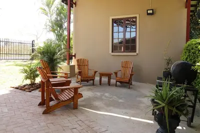 a patio with chairs and a table and a window at The Goat House Farmstay in Nelspruit