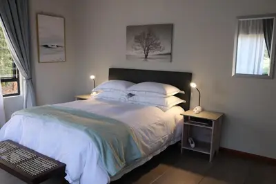 a bedroom with a bed with white sheets and pillows at The Goat House Farmstay in Nelspruit