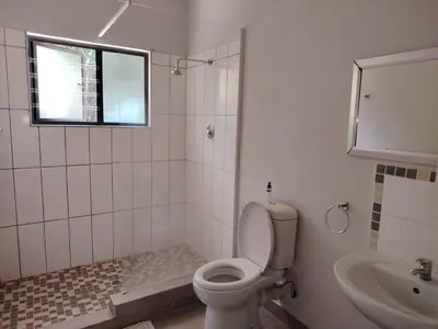 a bathroom with a toilet and a sink and a window at The Goat House Farmstay in Nelspruit