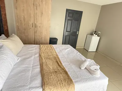 a bedroom with a white bed with a blanket on it at Home Away Nest B&B in Witbank