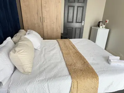 a bed with white sheets and pillows on it at Home Away Nest B&B in Witbank