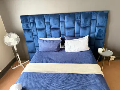 a bedroom with a blue bed with a blue headboard at Home Away Nest B&B in Witbank