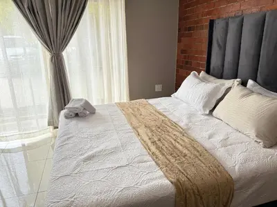 a bedroom with a large bed and a window at Home Away Nest B&B in Witbank