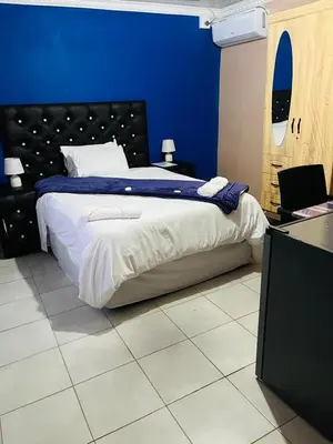 a bedroom with a large bed with a blue wall at AA Nkhumeleni Guesthouse and Accomodation in Thohoyandou