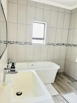 a white bathroom with a tub and a window at The Prestige Home in Middelburg