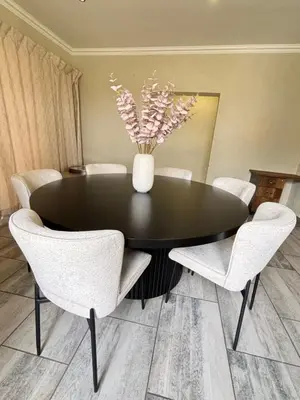 a black dining room table with white chairs and a vase with flowers at The Prestige Home in Middelburg