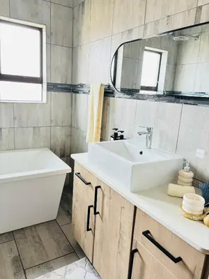 a bathroom with a sink and a tub and a mirror at The Prestige Home in Middelburg