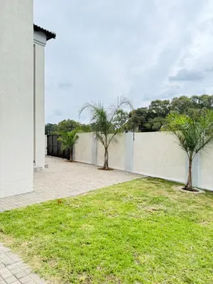 a white wall with two trees in a yard at The Prestige Home in Middelburg