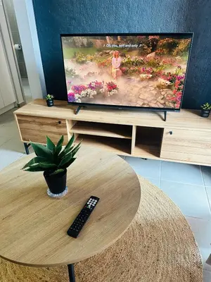 a television on a stand with a remote control on a table at Calm & Cozy Apartment 3 in Pretoria
