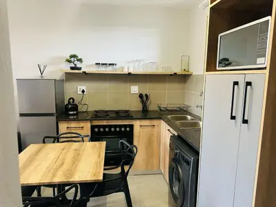 a small kitchen with a wooden table and a counter top at Calm & Cozy Apartment 3 in Pretoria