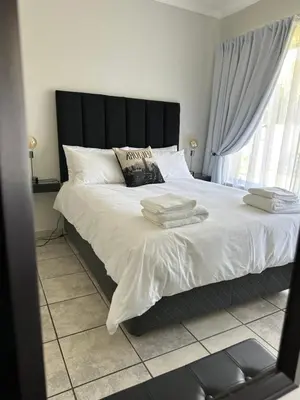a bedroom with a large bed with two towels on it at AfriSky guest house in Kempton Park