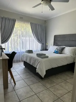 a bedroom with a bed with a fan and a window at AfriSky guest house in Kempton Park