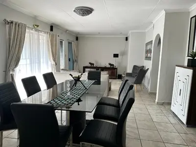 a dining room with a glass table and black chairs at AfriSky guest house in Kempton Park