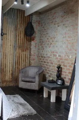 a living room with a chair and a table at Shiloh Bush Cottage in Nelspruit